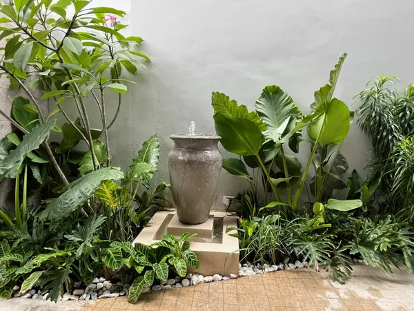 Indoor pocket garden with clay jar water fountain surrounded by tropical plants in Quezon City