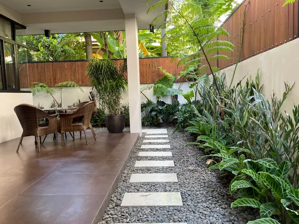 Side garden with stepping stone path, ferns, and rattan dining set at Hillsborough Alabang Village