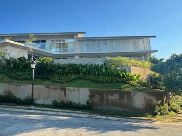 Tropical planting and lawn on a sloping lot above a retaining wall in Ayala Westgrove Heights, Silang
