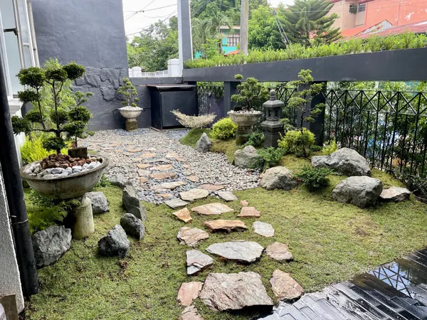 Japanese-inspired garden with stone pathway, bonsai trees, and stone lantern at United Hills Parañaque